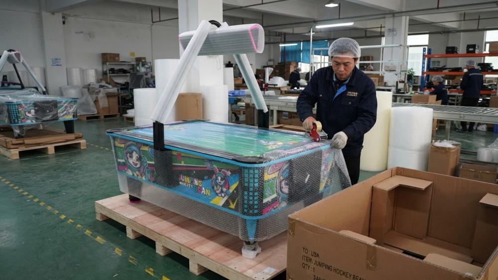 Workers packing a commercial air hockey table for export shipment