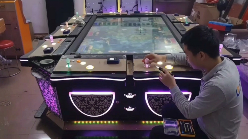 Engineer testing player controls and screen output on a fish game PCB system