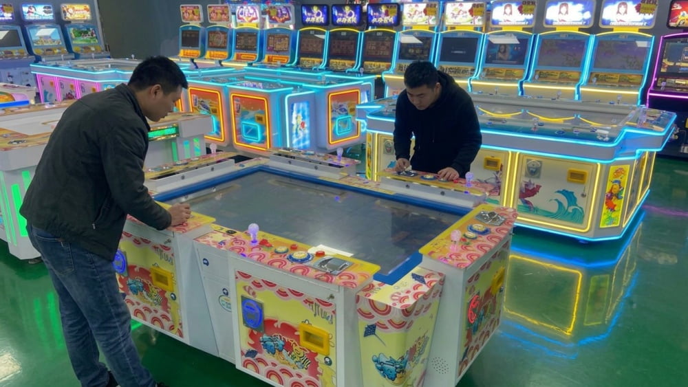 Staff member checking a payment device and player screen on a fish game machine